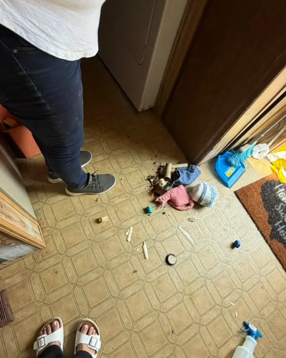 Kitchen floor covered in trash and clutter before cleaning